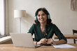 © fizkes - Woman radio host in headphones sit at desk with microphone and laptop, take part in online conference, videocall, look at camera. Portrait of blogger, influencer, streamer, record webinar or podcast