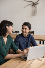 Canvas Print - Multi ethnic women colleagues laughing in office at workplace desk, share thoughts, ideas, opinions enjoy break and pleasant informal talk during workday, having successful teamwork, enjoy friendship