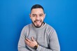 © Krakenimages.com - Hispanic man standing over blue background smiling and laughing hard out loud because funny crazy joke with hands on body.