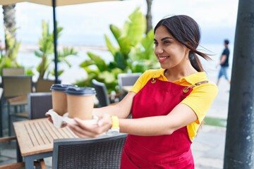 Poster - Young beautiful arab woman waitress smiling confident holding take away coffee at coffee shop terrace