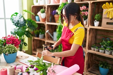 Poster - Young beautiful arab woman florist cutting plant at flower shop