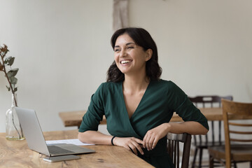 Young successful businesslady sit at desk with laptop, laughs, feel happy, satisfied with career growth and professional achievement, small business owner, individual entrepreneur, freelancer portrait