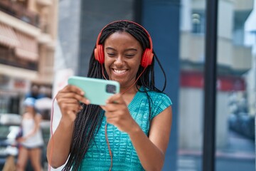 Wall Mural - African american woman smiling confident playing video game at street