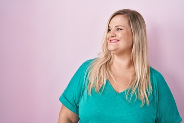 Poster - Caucasian plus size woman standing over pink background looking away to side with smile on face, natural expression. laughing confident.