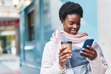 Wall Mural - African american woman using smartphone drinking coffee at street