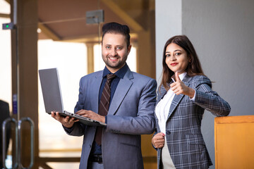 Wall Mural - Young indian business woman or manager showing thumps up with young businessman at office.