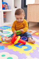 adorable caucasian baby playing with hoops sitting on floor at kindergarten