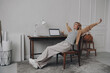 © gstockstudio - Relaxed woman keeping arms outstretched while sitting at her creative working place