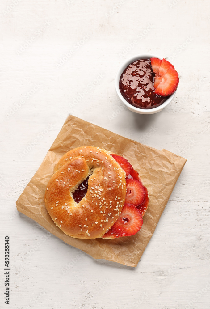 Tasty bagel with sesame and strawberry jam on light background