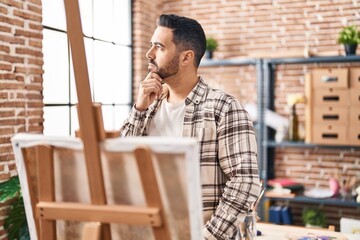 Sticker - Young hispanic man looking draw with doubt expression at art studio