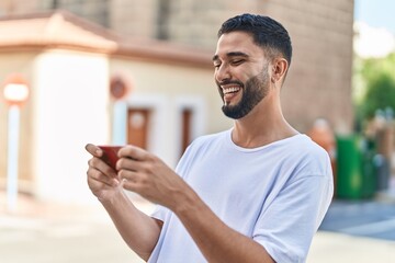 Wall Mural - Young arab man smiling confident watching video on smartphone at street