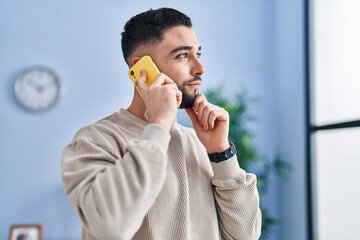 Sticker - Young arab man talking on the smartphone with doubt expression at home