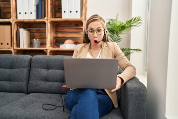 Poster - Young blonde woman working on online appointment scared and amazed with open mouth for surprise, disbelief face