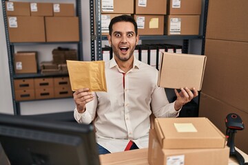 Sticker - Young hispanic man with beard working at small business ecommerce holding delivery packages celebrating crazy and amazed for success with open eyes screaming excited.