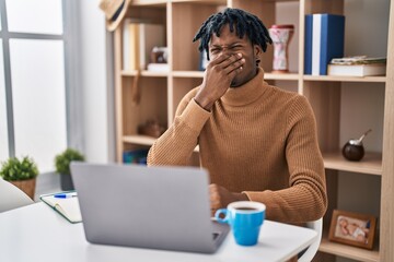 Sticker - Young african man with dreadlocks working using computer laptop smelling something stinky and disgusting, intolerable smell, holding breath with fingers on nose. bad smell