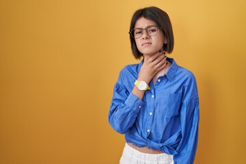 Poster - Young girl standing over yellow background touching painful neck, sore throat for flu, clod and infection