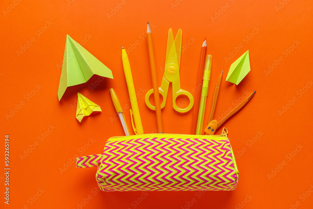 Composition with stationery supplies and paper plane on orange background