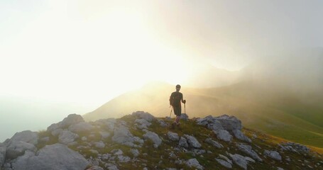 Wall Mural - young man hiking on ridge edge of the mountain in abruzzo italy with poles at sunset