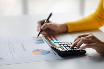 Wall Mural - Businessman using a calculator to calculate numbers on a company's financial documents, she is analyzing historical financial data to plan how to grow the company. Financial concept.