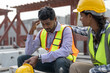 © Supachai - Asian Indian man worker feeling sad and upset while sitting at construction site. Female worker colleague supporting and consolation him.