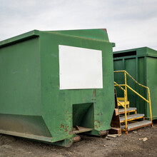 Green Steel Industrial Container With A White Blank Sign At Recycling Center