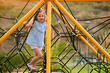 © CSRRDRGZ - Niña hermosa latina rubia jugando y disfrutando subiendo y disfrutando de escalar y trepar un juego en las alturas al aire libre en un hermoso día soleado al atardecer en el parque