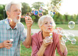 © Lumos sp - woman man senior couple  together elderly active happy retirement bubble soap blowing fun blow vitality bonding park outdoor leisure park fun
