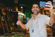 © juanpablo - Middle-aged Latin man making a video call from his vegetable store. Copy space.
