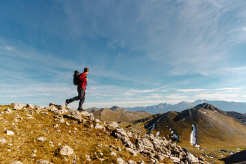 white male mountaineer with red clothes and backpack ascending a mountain peak during a hiking route on a sunny day. concept of sport and outdoor adventure. travel.