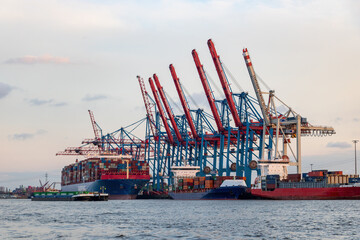 Huge container ship in the harbour of Hamburg, 400m long, sunset shot.
