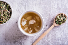 Close Up Of Cold Green Japanese Hojicha Tea With Ice In Cups And Dry Tea In A Bowl Top View