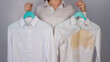 © Михаил Решетников - A woman compares two white shirts before and after washing. The girl is holding one blouse, clean and ironed, and the other, dirty with coffee stains