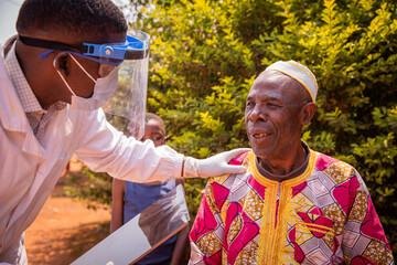 an african doctor talks to an elderly patient during a medical examination