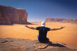 Wadi Rum w Jordanii. Mężczyzna siedzący na pustynnej skale patrzący w dal.