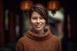 Headshot portrait photography of a grinning woman in her 30s wearing a cozy sweater against an ancient temple or shrine background. Generative AI