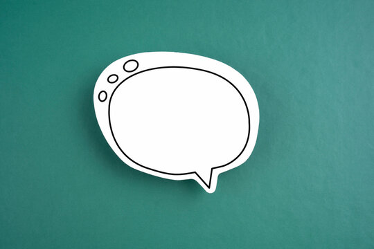 The White speech bubble shaped post it note on green background with copy space.