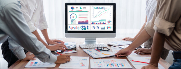 Leinwandbilder - Analyst team utilizing BI Fintech to analyze and pointing at financial dashboard paper office. Businesspeople examining report paper on table for business insight. Panorama shot. Scrutinize
