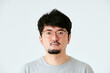 白背景で眼鏡をかけた髭を生やしたカメラ目線の30代の1人の日本人男性の人物の上半身の正面