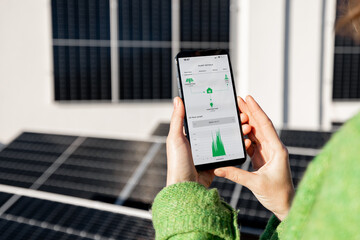 woman monitors energy production from the solar power plant with mobile phone. close-up view on phon