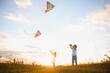 © Serhii - Happy children launch a kite in the field at sunset. Little boy and girl on summer vacation.