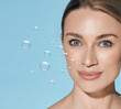 © Peakstock - Skin moisturizing concept. Water drops on face of beautiful woman with fresh hydrated and moisturized skin, on blue background