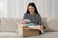 Happy Woman Holding Greeting Card Near Parcel With Christmas Gift At Home