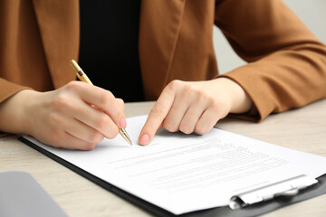 Canvas Print - Woman signing document at wooden table, closeup