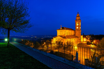 Wall Mural - Illuminated parish church under blue morning sky in small italian town.