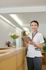 Sticker - Joyful spa salon receptionist checking schedule on tablet computer before opening