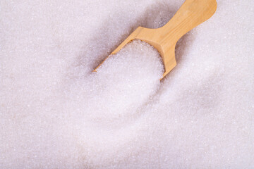 Wall Mural - White granulated sugar. Top view wooden spoon inside heap of white refined sugar