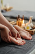 © DragonImages - Therapist massaging feet of client with oils