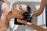 Hairdresser washing hair of client with moisturizing shampoo