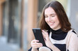 © PheelingsMedia - Happy woman using cell phone standing in the street