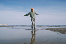 Happy Woman Running On Shore At Beach